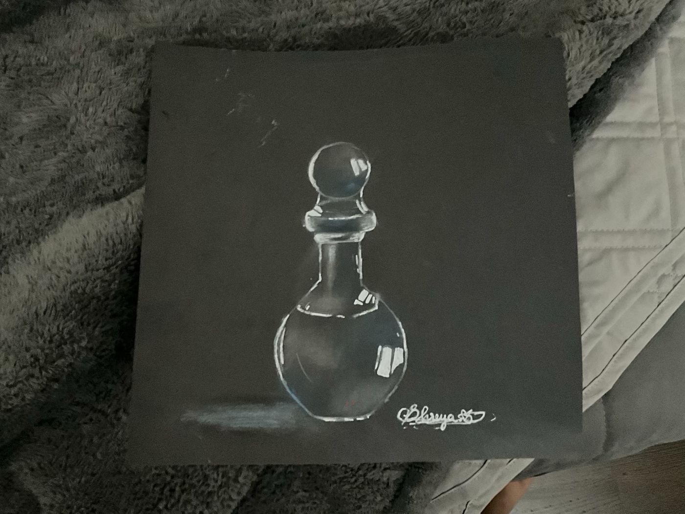 Graphite study of a glass perfume bottle on dark paper.