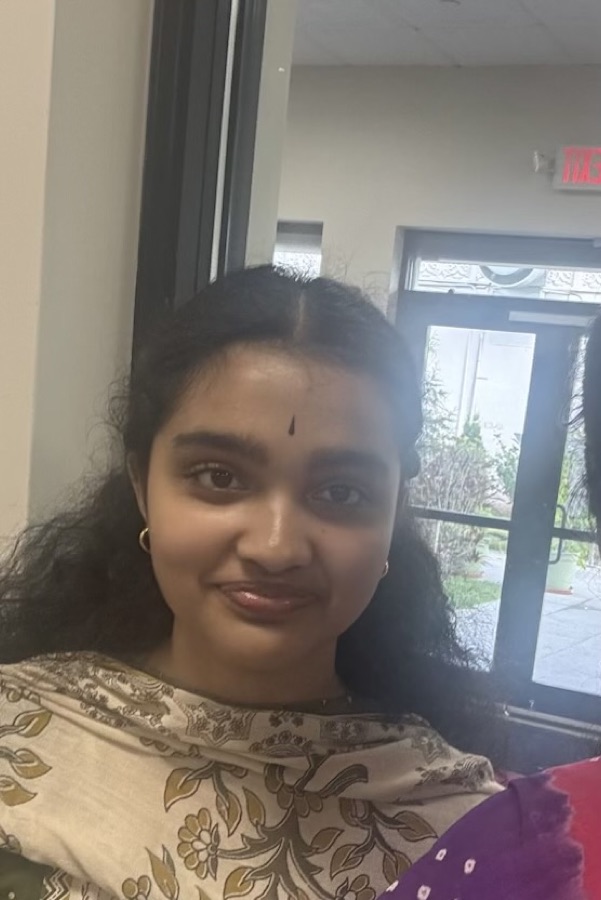 Shreya smiling in a cream kalamkari-print kurta, in a hall with glass doors onto a garden behind her.